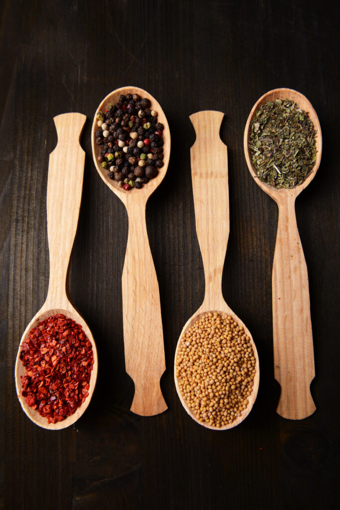 different spices in spoons on wooden background different spices in spoons on wooden background